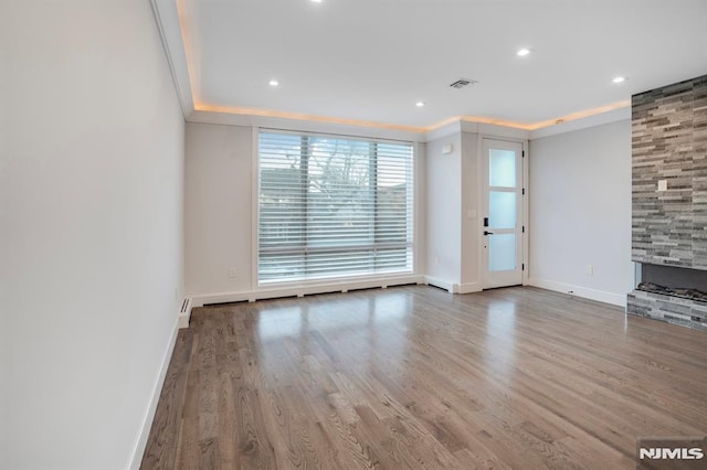 unfurnished living room featuring a fireplace, wood-type flooring, and crown molding