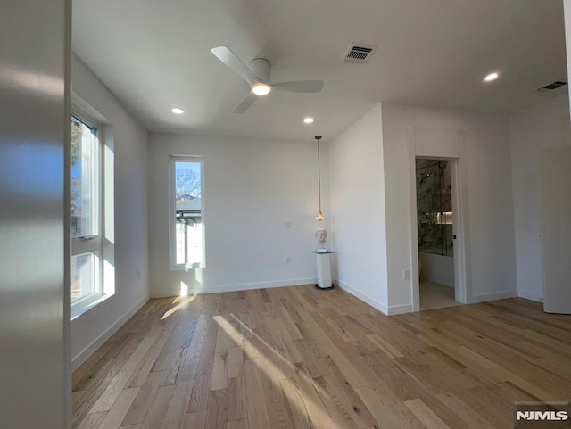 empty room with ceiling fan and light hardwood / wood-style flooring