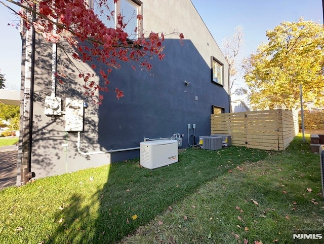 view of side of home featuring central air condition unit and a lawn