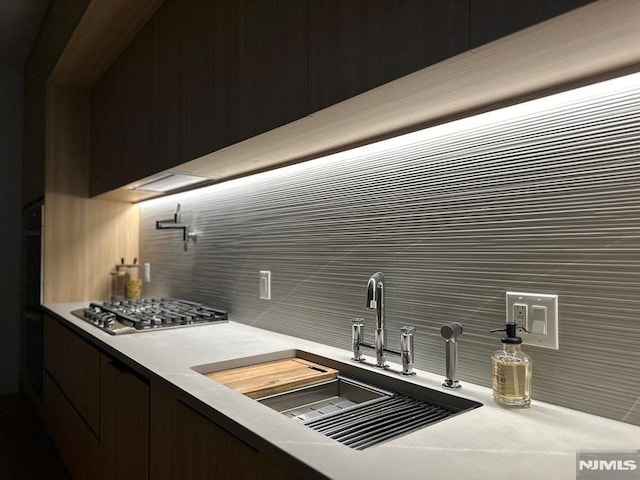 kitchen featuring tasteful backsplash, sink, and stainless steel gas stovetop