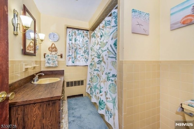 bathroom featuring radiator heating unit, vanity, tile walls, and curtained shower