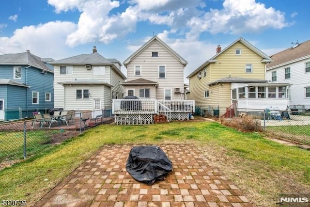 rear view of house with a fire pit, a yard, a patio, and a wooden deck