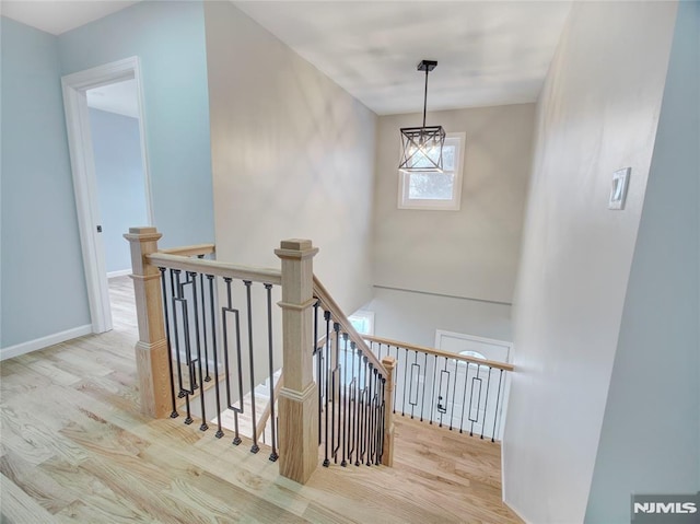 stairway with hardwood / wood-style floors and a notable chandelier