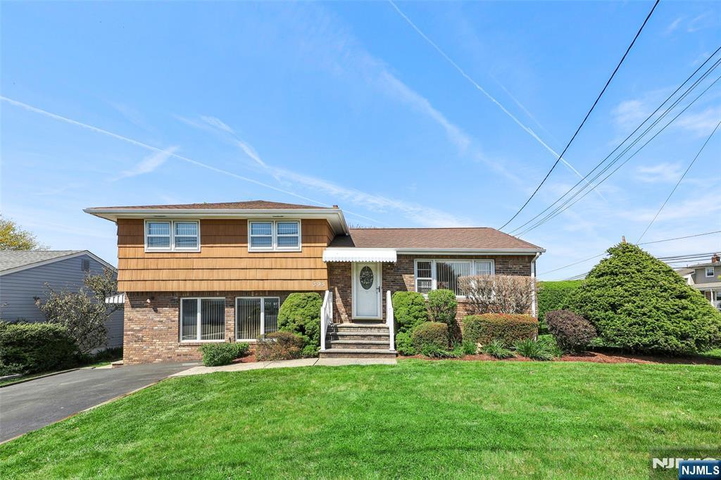 tri-level home with brick siding and a front lawn