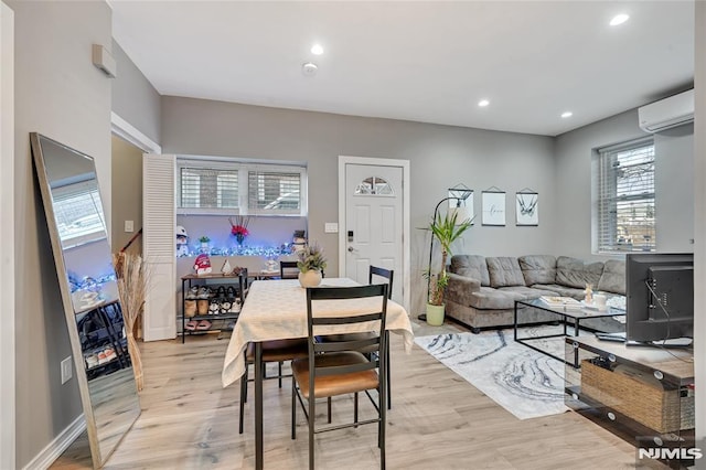 dining room with a wall mounted air conditioner and light hardwood / wood-style flooring