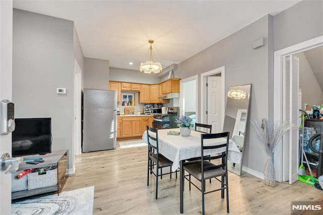 dining room with light hardwood / wood-style floors and a notable chandelier