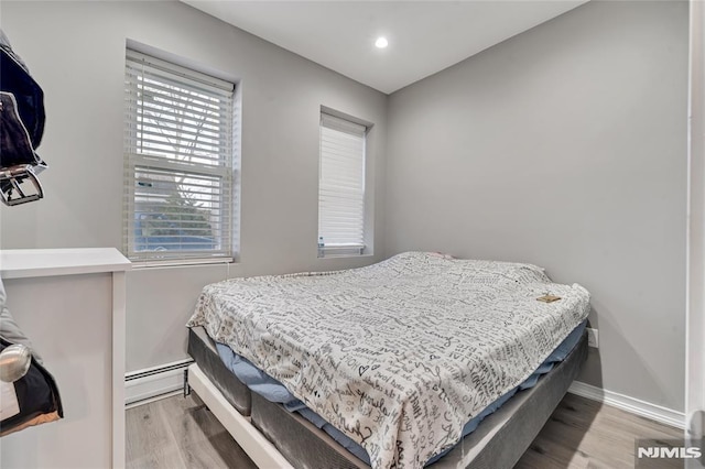 bedroom with baseboard heating and light wood-type flooring