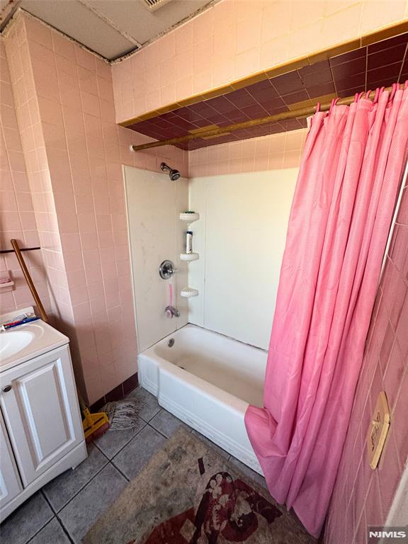 bathroom with tile patterned floors, vanity, shower / tub combo with curtain, and tile walls