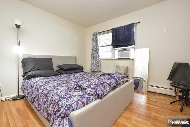 bedroom with hardwood / wood-style flooring, cooling unit, and a baseboard radiator