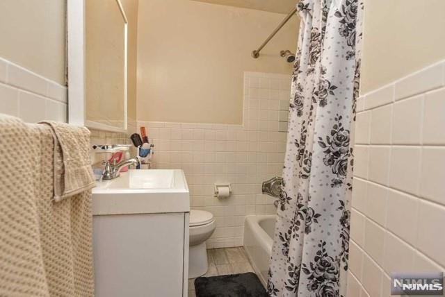 full bathroom featuring shower / tub combo, vanity, tile walls, and toilet