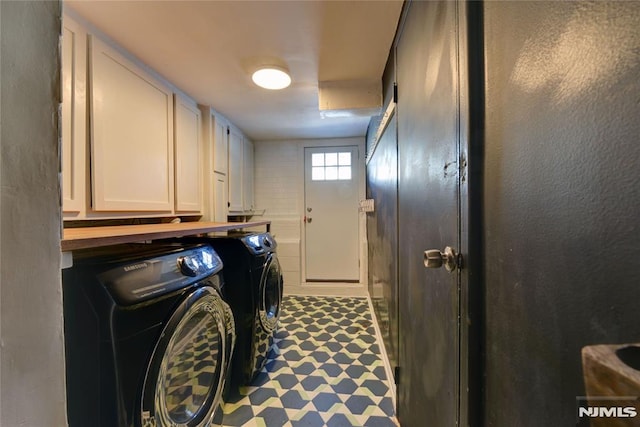 clothes washing area featuring washer and dryer and cabinets