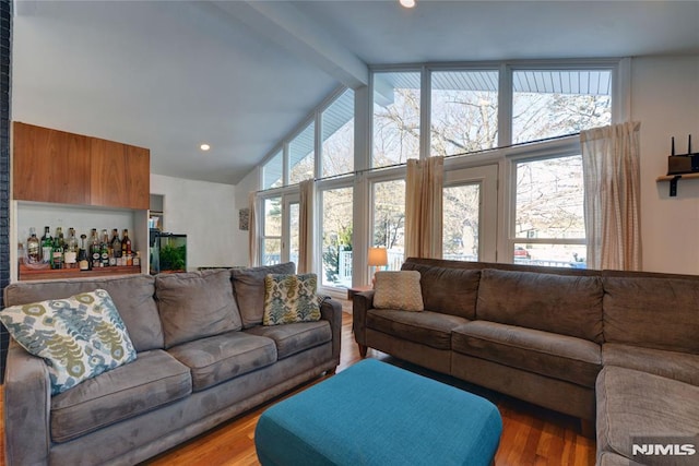 living room featuring beam ceiling, bar, a healthy amount of sunlight, and hardwood / wood-style flooring