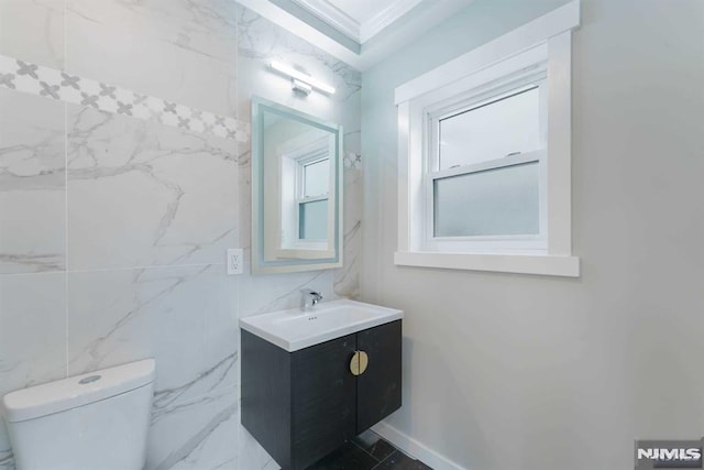 bathroom featuring tile walls, toilet, vanity, and ornamental molding