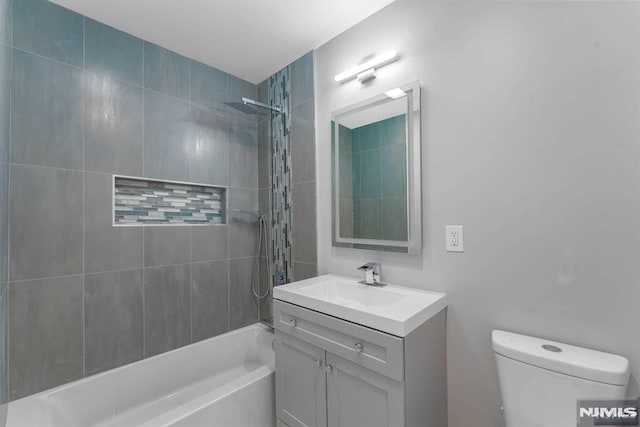 full bathroom with tiled shower / bath combo, toilet, and vanity