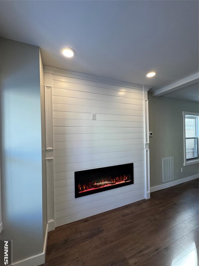 unfurnished living room featuring dark wood-type flooring and a large fireplace