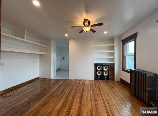 unfurnished living room featuring ceiling fan, radiator heating unit, and hardwood / wood-style floors