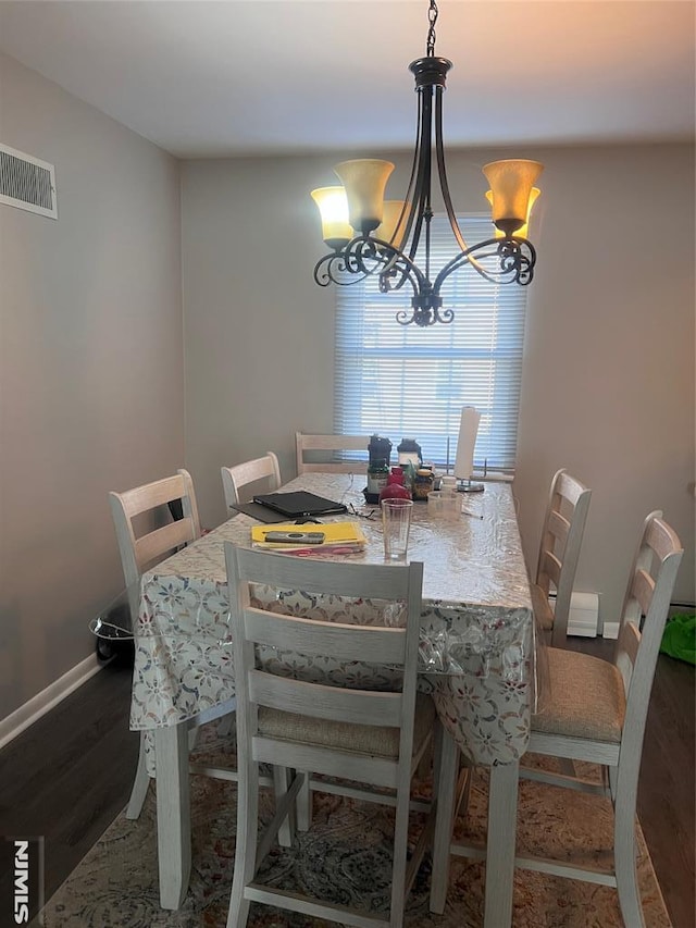 dining room with dark wood-type flooring and a chandelier