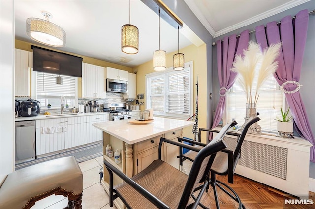 kitchen with sink, white cabinetry, hanging light fixtures, and appliances with stainless steel finishes