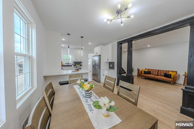 dining room featuring light wood-type flooring, plenty of natural light, and a notable chandelier