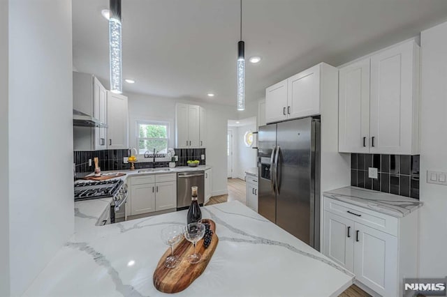 kitchen featuring white cabinets, kitchen peninsula, stainless steel appliances, and hanging light fixtures