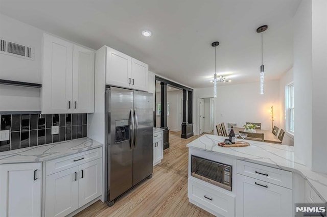 kitchen featuring white cabinets, decorative light fixtures, light stone counters, and appliances with stainless steel finishes