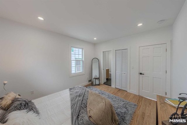 bedroom with light hardwood / wood-style floors and two closets