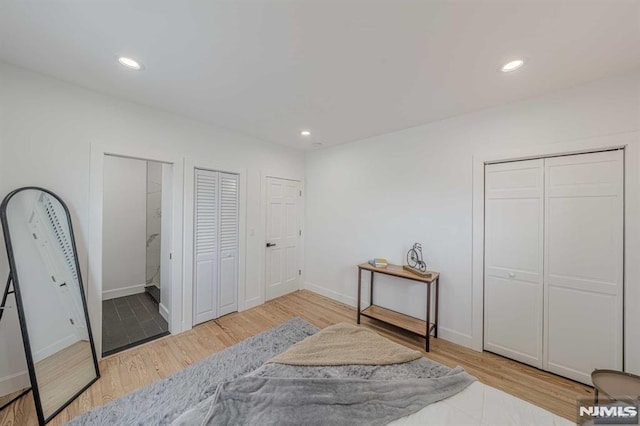 bedroom featuring light hardwood / wood-style floors and multiple closets