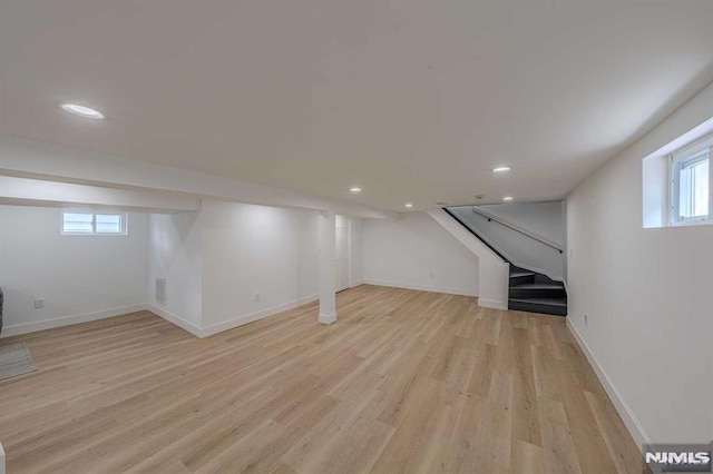 basement with plenty of natural light and light hardwood / wood-style floors