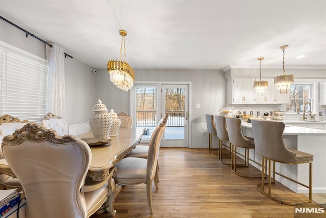 dining space with sink, a notable chandelier, and light wood-type flooring