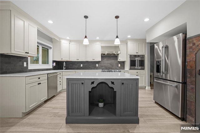 kitchen featuring wall chimney exhaust hood, stainless steel appliances, sink, decorative light fixtures, and a center island