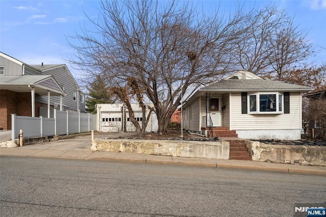 view of front of house with entry steps, a garage, fence, driveway, and roof with shingles