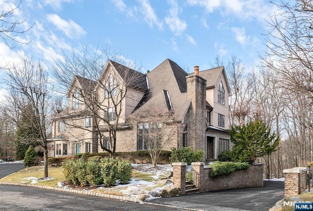 exterior space with brick siding, a chimney, and stucco siding