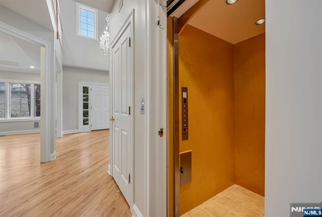 hallway featuring recessed lighting, elevator, baseboards, and light wood finished floors