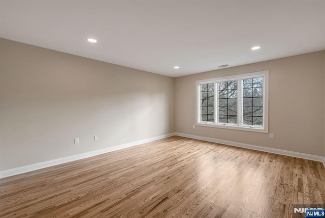 empty room featuring light wood-type flooring, visible vents, baseboards, and recessed lighting