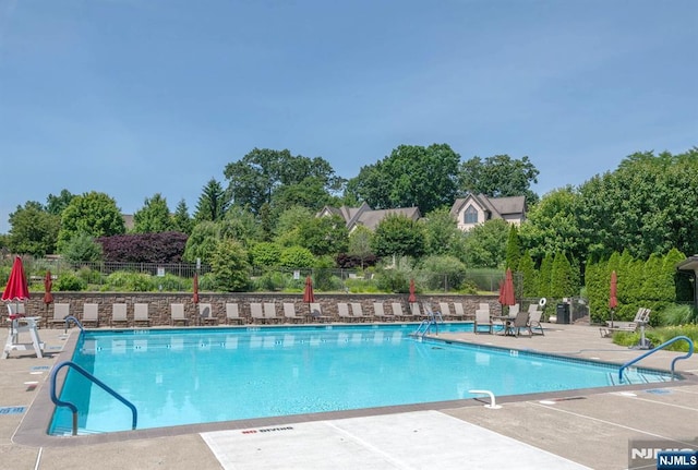 community pool featuring fence and a patio