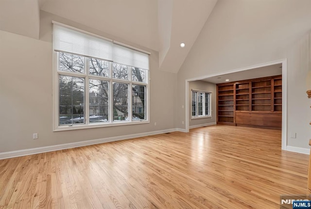 unfurnished living room featuring light wood-type flooring, baseboards, high vaulted ceiling, and recessed lighting