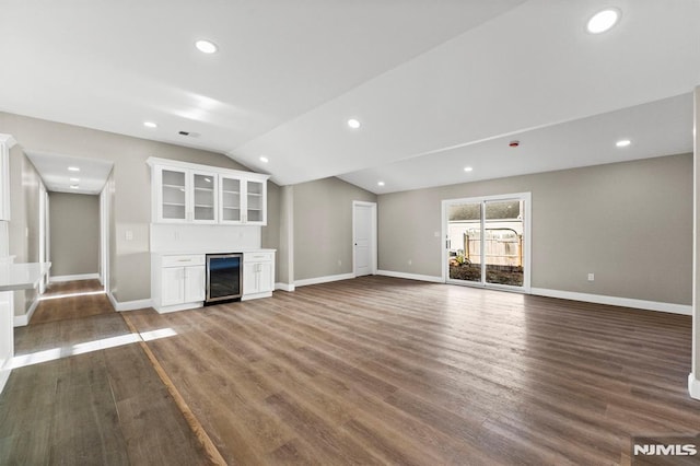 unfurnished living room with dark hardwood / wood-style floors, lofted ceiling, and wine cooler