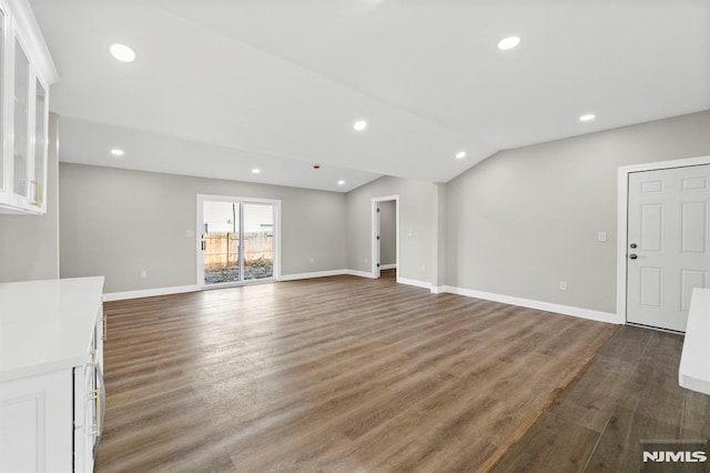 unfurnished living room with dark wood-type flooring and lofted ceiling