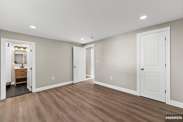 unfurnished bedroom with dark hardwood / wood-style flooring, connected bathroom, and sink