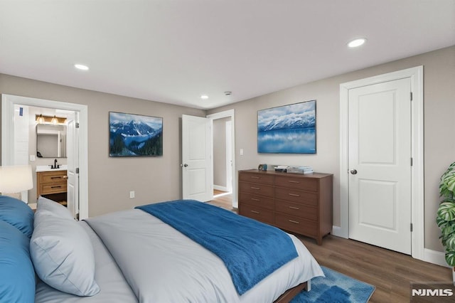 bedroom with dark hardwood / wood-style flooring, sink, and ensuite bath