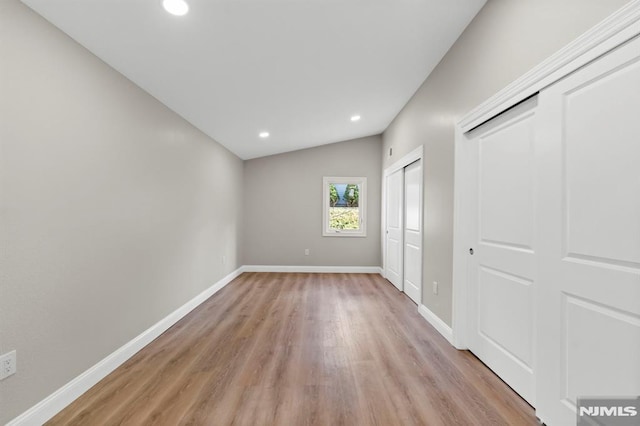 unfurnished bedroom with light hardwood / wood-style flooring and lofted ceiling