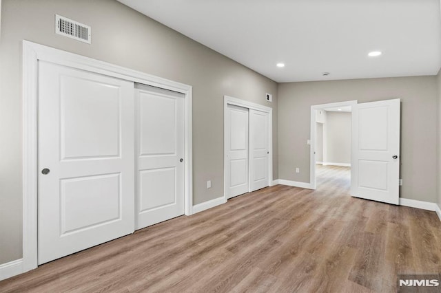 unfurnished bedroom featuring light hardwood / wood-style floors and lofted ceiling