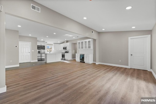 unfurnished living room with light hardwood / wood-style flooring and beverage cooler