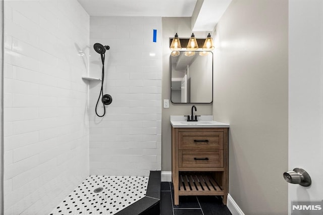 bathroom with a tile shower, tile patterned flooring, and vanity