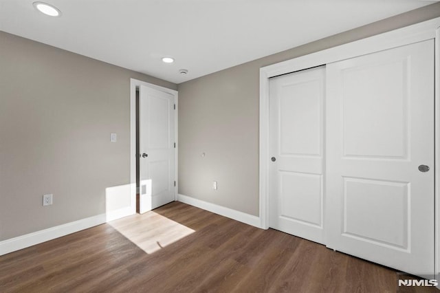 unfurnished bedroom with dark hardwood / wood-style floors and a closet