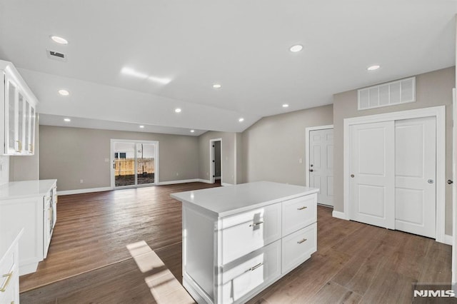 kitchen featuring vaulted ceiling, white cabinetry, a kitchen island, and dark hardwood / wood-style floors