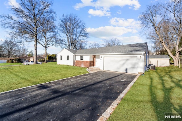 view of front of home featuring a front yard, a garage, and central AC unit