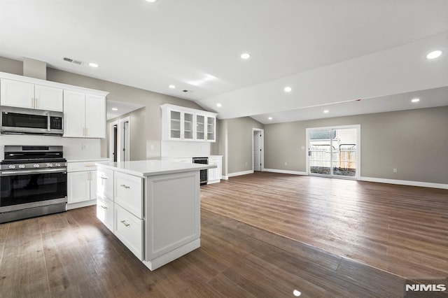 kitchen with a center island, lofted ceiling, dark wood-type flooring, white cabinets, and appliances with stainless steel finishes