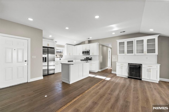 kitchen with white cabinets, stainless steel appliances, beverage cooler, and lofted ceiling