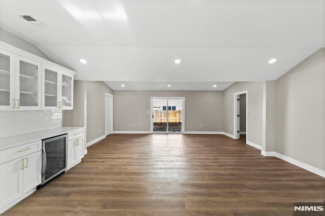 unfurnished living room featuring dark hardwood / wood-style flooring, lofted ceiling, and beverage cooler